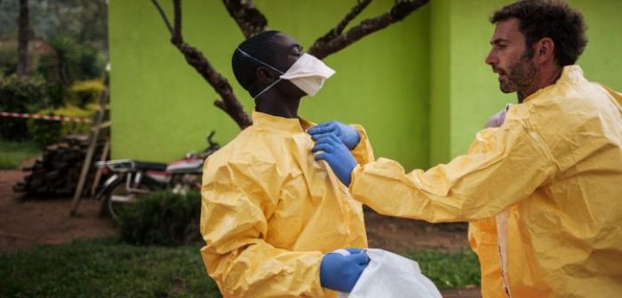 Luca Fontana, especialista en higiene de MSF, explica a un miembro del personal cómo vestirse con el traje protector para que los equipos sanitarios no corran ningún riesgo de exposición al virus de Ébola.Alexis Huguet