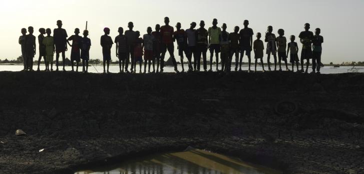Imagen de archivo de 2022: Unos niños sobre un dique en Rubkona, Sudán del Sur, que impide que toda la ciudad se inunde. Si bien las graves inundaciones en la región se deben a múltiples factores, el cambio climático es definitivamente uno de ellosPeter Caton.