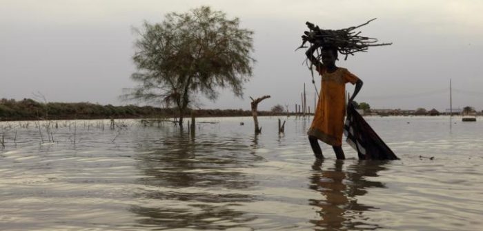 Una niña camina entre las aguas de la inundación mientras carga leña para su hogar en Rubkona, Sudán del Sur. Peter Caton.