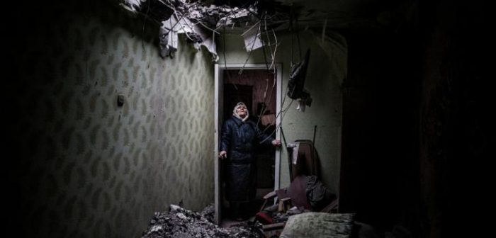Galina, de 86 años, mira el hueco que dejó un proyectil en su casa de Donetsk. © Manu Brabo