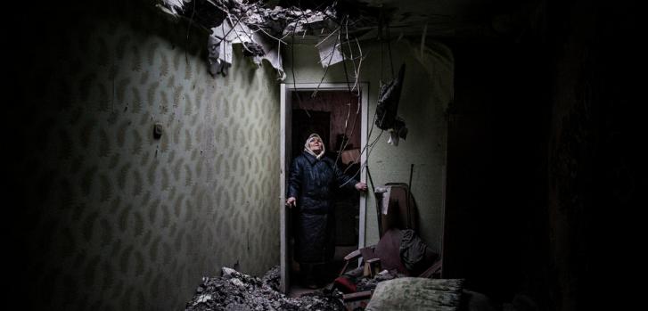 Galina, de 86 años, mira el hueco que dejó un proyectil en su casa de Donetsk. © Manu Brabo