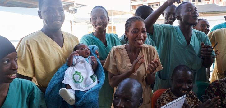 Ibrahima, el primer sobreviviente de ébola en Guinea sostiene en brazos a Nubia, la última paciente de la epidemia y la primera recién nacida que logra curarse. ©Sam Phelps