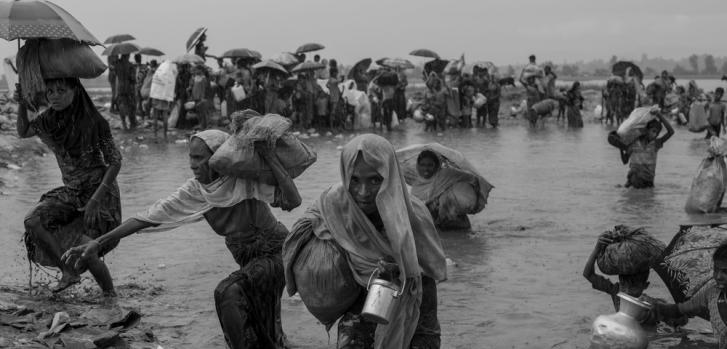 17 de octubre de 2017. Durante un momento de confusión, cuando la fuerte lluvia monzónica cayó cerca de la frontera entre Bangladesh y Myanmar, los refugiados rohingya pasan rápidamente por delante de los guardias fronterizos de Bangladesh que buscan evitar que continúen su viaje hacia los campos de refugiados cerca de Cox Bazar. ©Moises Saman