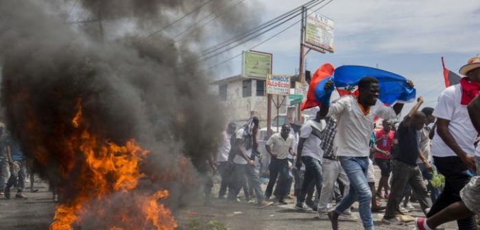 Varios manifestantes haitianos corren cerca de neumáticos en llamas durante una manifestación en Puerto Príncipe que pide la salida del presidente Jovenel Moïse, el 9 de junio de 2019.Jeanty Junior Augustin/MSF